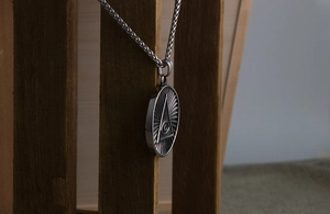 Gros plan d'un pendentif œil en acier inoxydable vintage avec chaîne en épi