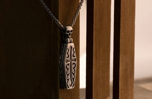 Detailed view of gothic coffin pendant with cross and skull on dark wood background