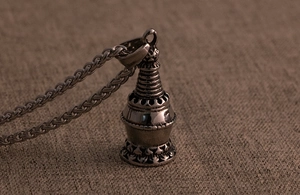Macro shot of retro pagoda pendant in antique silver stainless steel on textured fabric