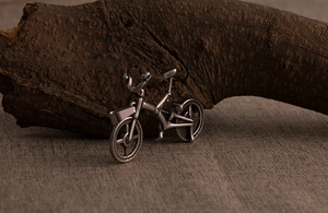 Macro shot of vintage silver titanium steel bicycle pendant on rustic wood and linen