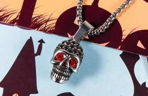 Macro shot of skull pendant with red stone eyes on a box chain for Halloween