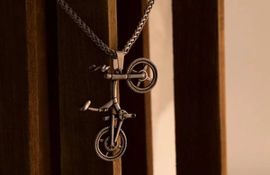 Macro shot of vintage titanium steel BMX bicycle pendant with industrial chain on wood