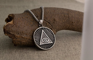 Gros plan du pendentif œil omniscient vintage en acier titane sur chaîne de blé
