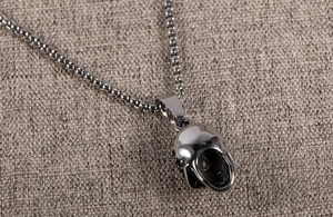 Macro shot of skull pendant necklace with red eye detail and stainless steel box chain