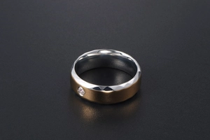 Détail de la bague en titane bicolore montrant le poli argenté, l'aspect mat doré et le diamant