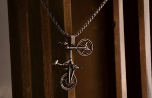 Macro shot of retro steel bicycle pendant featuring industrial details on vintage wood