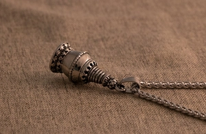 Macro view of vintage silver pagoda pendant with detailed relief on brown linen texture