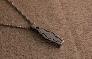 Macro shot of gothic coffin pendant with intricate vine relief on a woven wheat chain