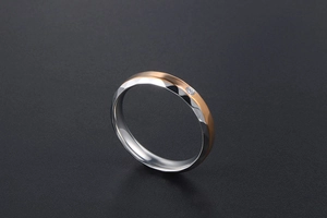 Détail d'une bague bicolore en titane avec facettes argentées, or rose et une petite pierre