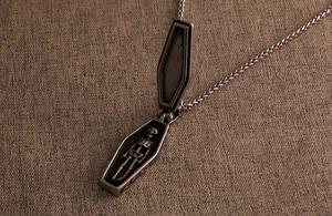 Macro detail of gothic coffin necklace featuring an opening lid and metal skeleton inside