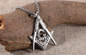 Detail of vintage Viking Freemason G compass pendant with ball chain on rustic fabric