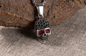 Detail of gothic skull necklace with red gemstone eyes on vintage stainless steel