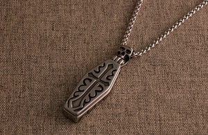 Detailed view of Gothic coffin pendant with skull detail and cross engraving on chain