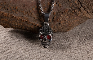 Macro view of vintage skull pendant with red rhinestone eyes and retro oxidized texture