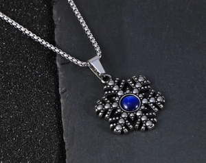 Macro-opname van sneeuwvlok hanger met blauwe steen en vintage stalen ketting