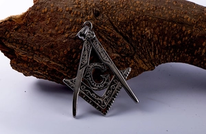 Macro detail of vintage titanium steel pendant featuring Freemasonry square and compass
