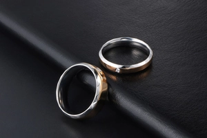 Gros plan de bagues de couple bicolores en acier avec oxyde de zirconium sur cuir noir
