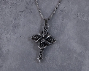 Dettaglio della collana gotica in acciaio con serpente intrecciato su croce d'argento