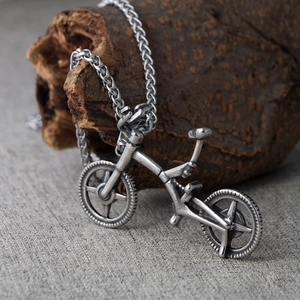 Retro silver bicycle pendant necklace with vintage finish on wood background