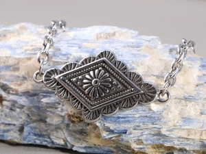 Dettaglio anello bohémien vintage in argento con incisione geometrica a rombi e finitura opaca