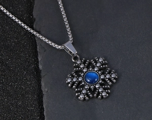 Macro detail van sneeuwvlok hanger met blauwe steen op donkere stenen achtergrond
