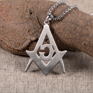 Vintage stainless steel Freemason pendant necklace with G symbol on a wooden background