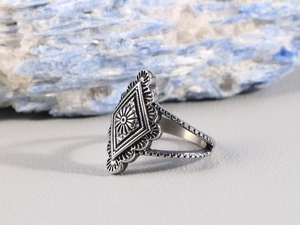 Dettaglio di anello vintage boho in acciaio con incisione a rombo e motivi floreali