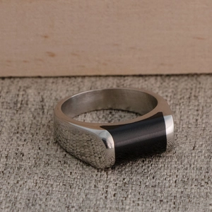 Gros plan d'une bague chevalière polie en acier inoxydable avec insert noir sur lin