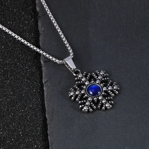 Kerst sneeuwvlok ketting in antiek zilver met blauwe kattenoog steen op zwarte stenen achtergrond