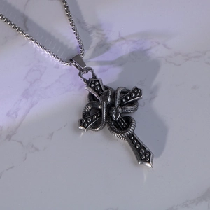 Collana vintage in acciaio inossidabile con pendente serpente e croce su marmo bianco