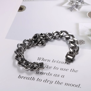 Macro detail of punk skull charm on a dark grey cuban chain bracelet for men