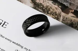 Détail d'une bague pour homme en acier noir avec texture tissée en fibre de carbone