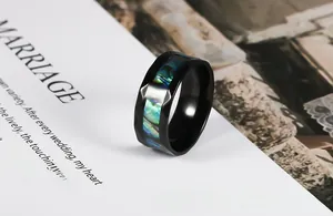 Macro detail of black stainless steel ring with colorful inlaid abalone shell and faceted edges