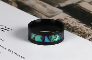Close-up of faceted black stainless steel ring with vibrant abalone shell inlay
