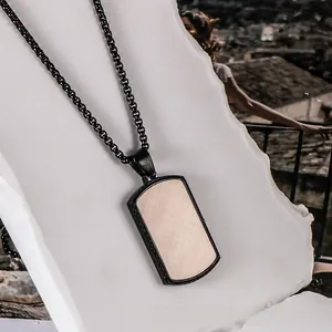 Detail of square black metal pendant with light brown wood grain texture on stone