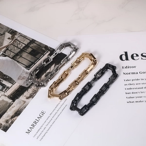 Three minimalist thick chain bracelets in silver, gold and black on a magazine