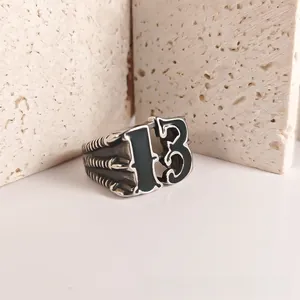 Detail of vintage punk stainless steel ring featuring black enamel number 13 and claw texture