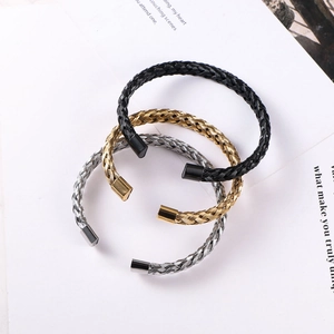 Flat lay of twisted wire stainless steel bangles in black, gold, and silver finishes