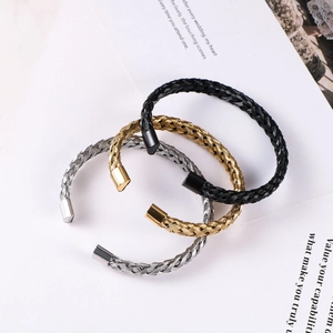 Three twisted stainless steel cable bracelets in silver, gold, and black colors