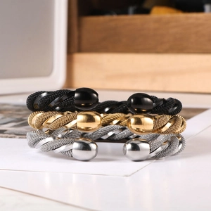 Detailed macro of woven stainless steel bangles in black, gold, and silver finishes
