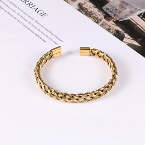 Detailed view of golden braided steel cable cuff bracelet with smooth end caps