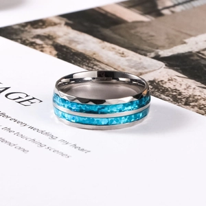 Macro detail of men's stainless steel ring with blue shell inlay and textured edges