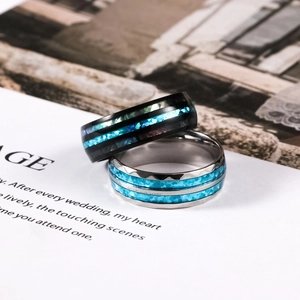 Detailed view of black and silver stainless steel rings with blue shell inlay on a book
