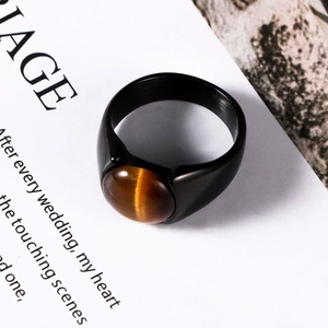 Men's black stainless steel ring featuring a round tiger eye stone on a minimalist background