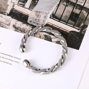 Detail of woven stainless steel cuff bracelet with silver braided texture and spherical ends