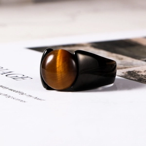 Macro shot of tiger eye gemstone ring with a sleek black metal band on magazine