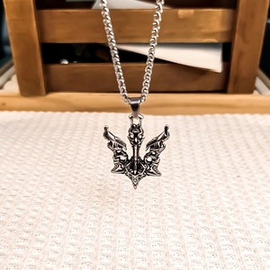 Collier rétro en acier inoxydable argenté avec pendentif trident en relief sur fond de tissu blanc