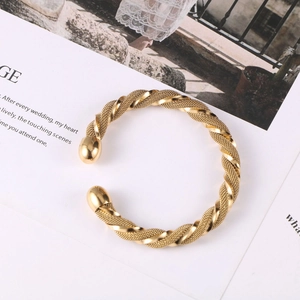 Detailed view of a gold-tone braided mesh bangle with twisted metal and spherical ends