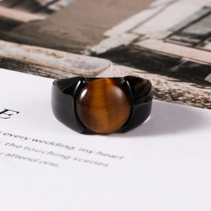 Macro shot of men's black polished ring featuring a large round brown tiger eye stone