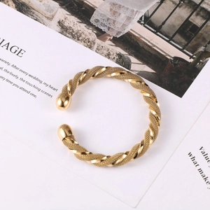 Detail of twisted gold mesh cuff bracelet with polished metal sphere end caps